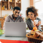 A couple sip coffee and use a laptop together.   